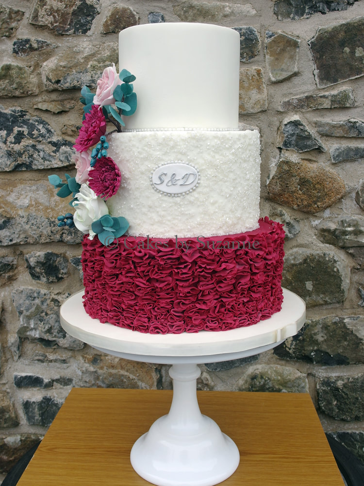 three tier round wedding cake with ruffles, sparkles and flowers