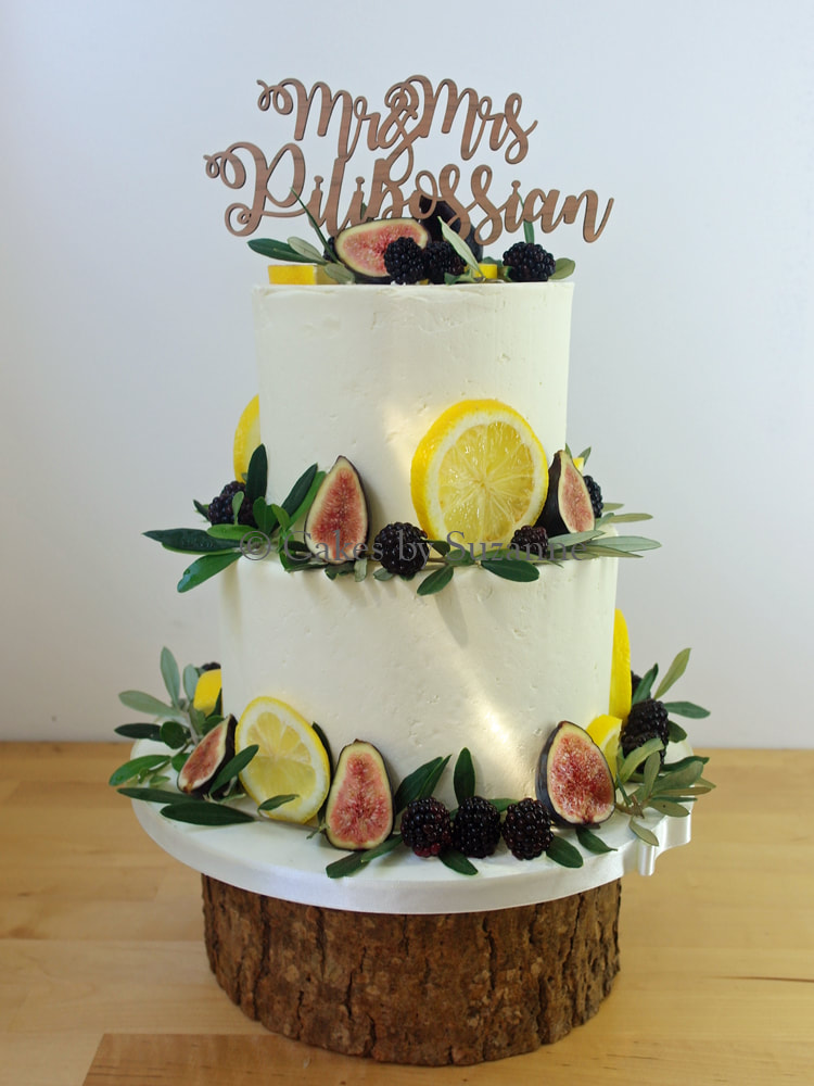 two tier round buttercream wedding cake with lemons, figs, blackberries, olive leaves