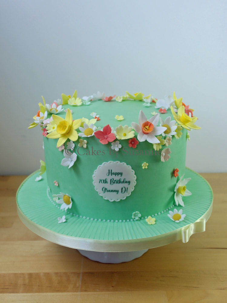 green birthday cake with daffodils, daisies and blossoms