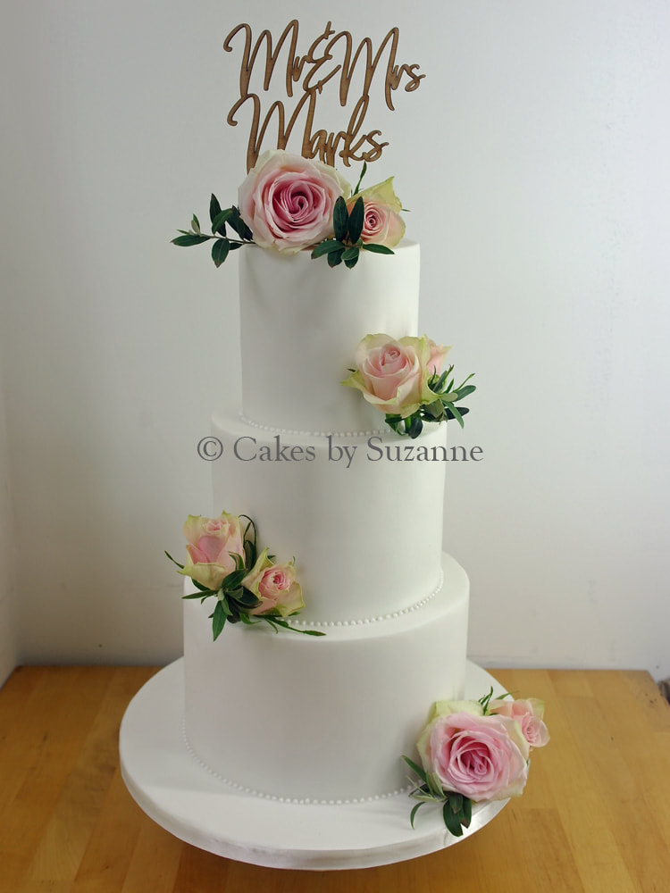 three tier round stacked wedding cake with personalised Mr and Mrs topper and fresh pink roses