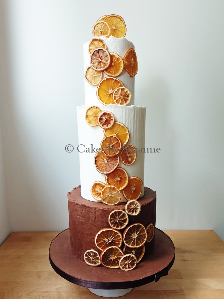 Vanilla and chocolate buttercream three tier round stacked cake with dried citrus orange and lemon slices