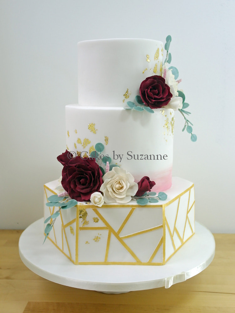 three tier round and hexagonal wedding cake with roses and gold
