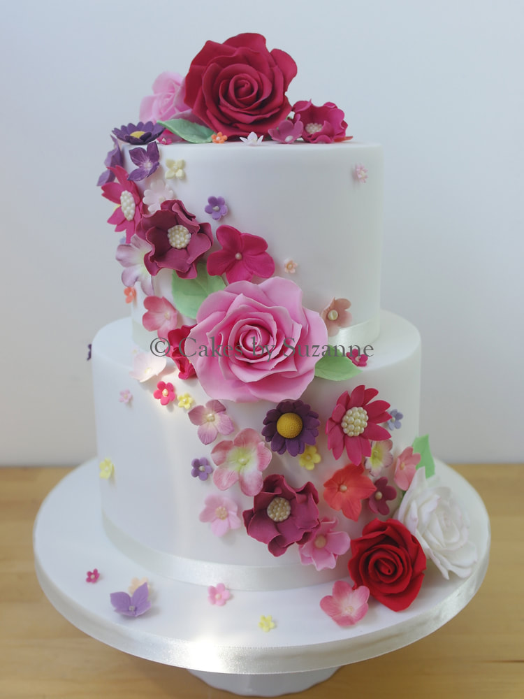 two tier round stacked wedding cake with bright sugar flower cascade