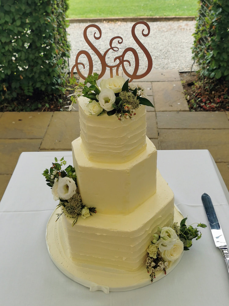 three tier rustic textured buttercream hexagonal wedding cake with fresh flowers