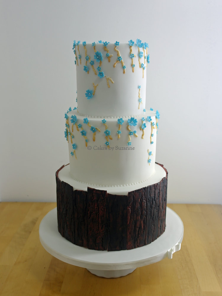 three tier round stacked wedding cake with bark effect bottom tier and forget me nots