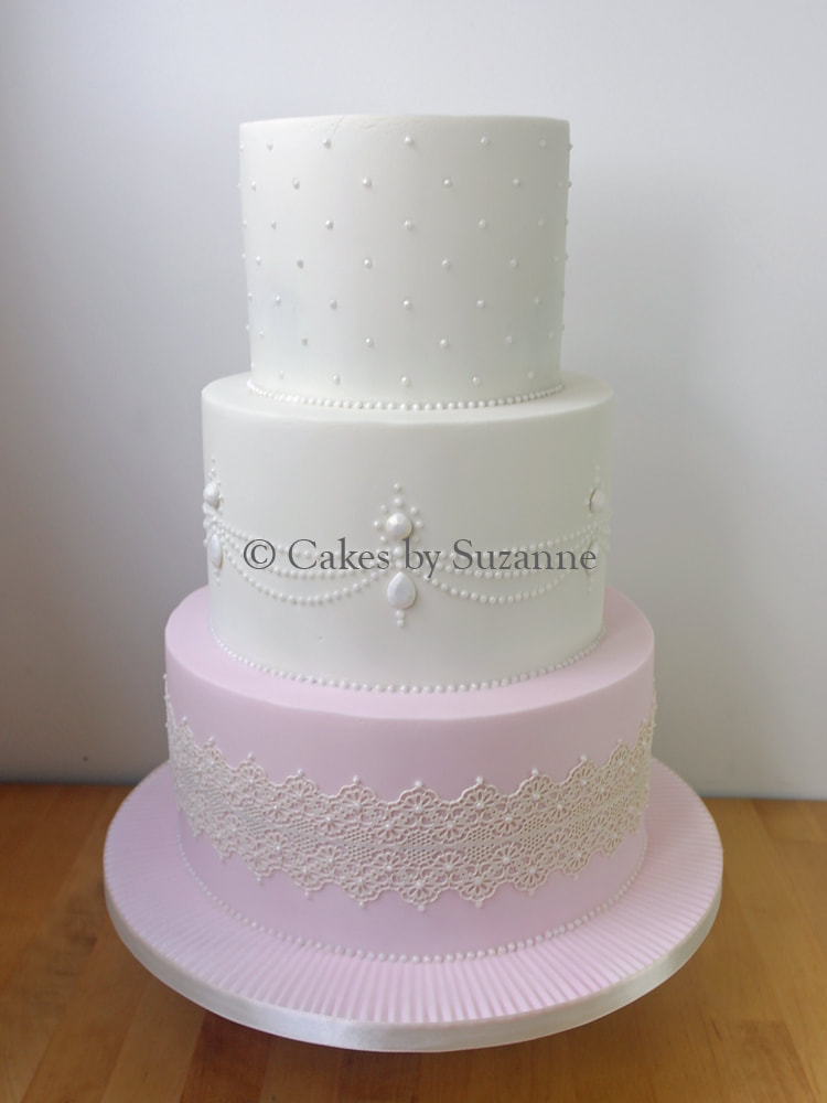 three tier round stacked wedding cake with sugar pearls and lace