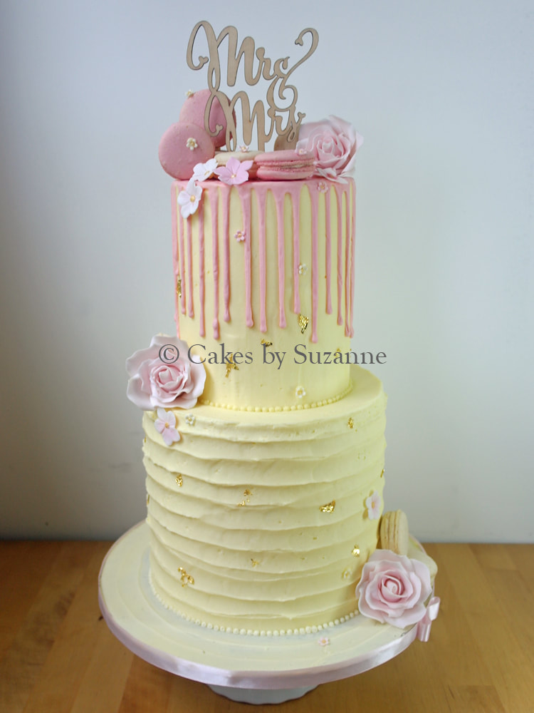 two double height tiers buttercream wedding cake with pink drip, macarons and sugar flowers