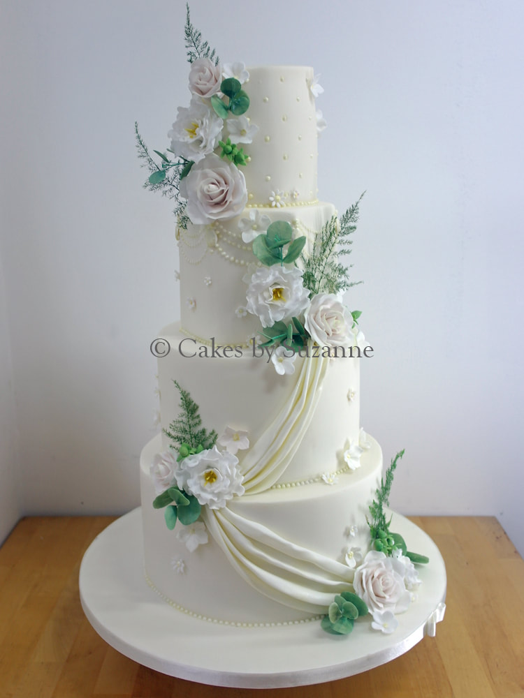 three tier round stacked wedding cake with sugar flowers and drapes