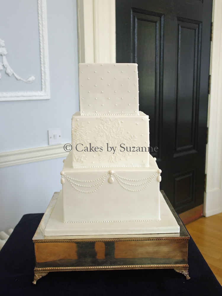 three tier square stacked wedding cake with sugar pearls and lace detail