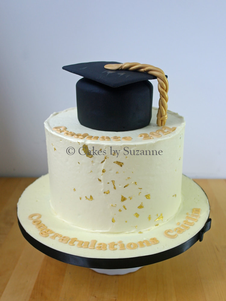graduation cake with mortarboard hat top tier and gold leaf detail