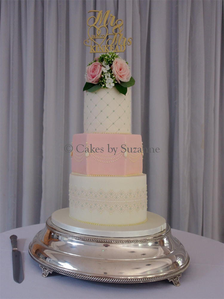 three tier round and hexagonal wedding cake decorated with fresh flowers