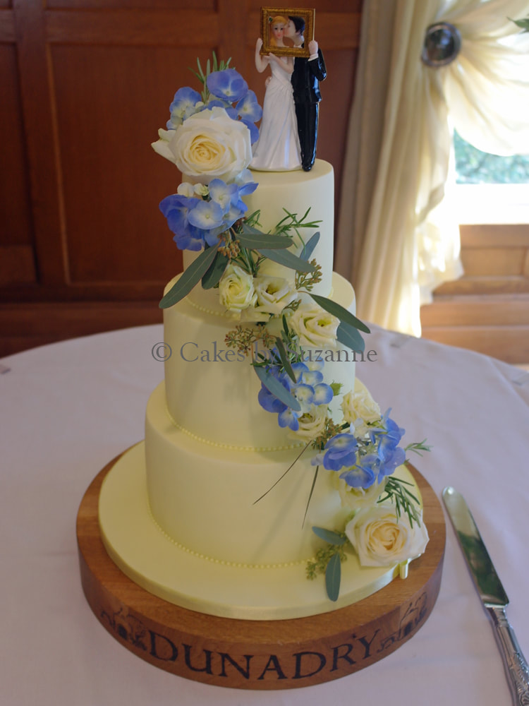 lemon three tier round stacked wedding cake with blue and lemon fresh flower cascade