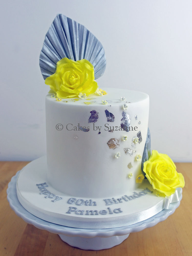 round 60th birthday cake with yellow roses and silver leaf
