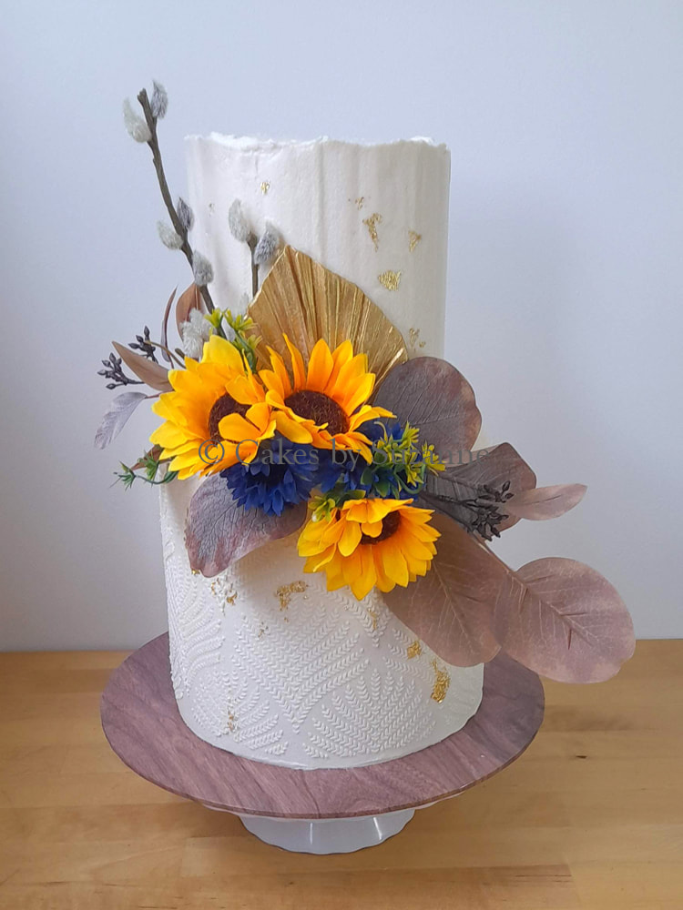 tall double height two tier round buttercream cake with sunflowers dried flowers leaves