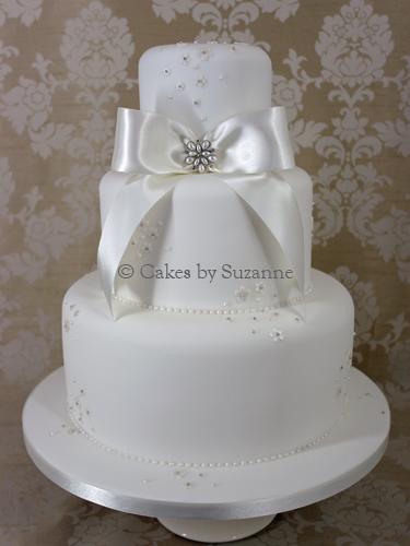 last minute three tier round wedding cake with bow, brooch and small blossoms.